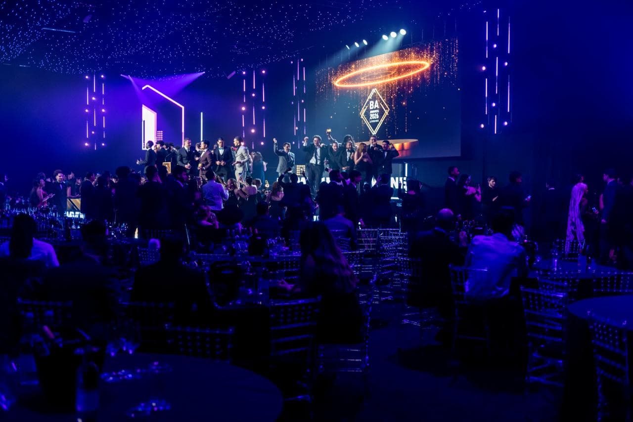 NLS OPTIMA team celebrating on stage at a gala event